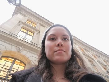 Portrait of young woman looking down against sky