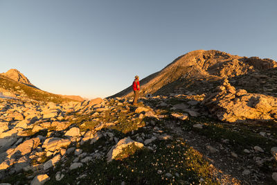 Male hiker standing on mountain against clear sky