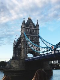 Low angle view of tower bridge against cloudy sky