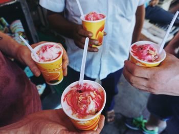 High angle view of friends holding dessert in glasses