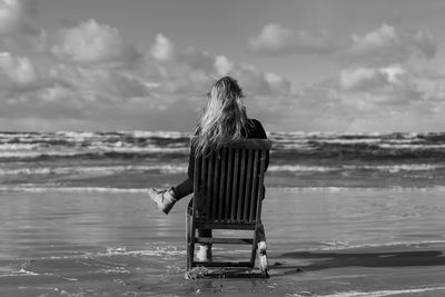 Rear view of woman on beach against sky