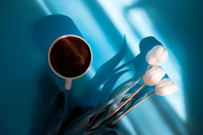 Directly above shot of flower with coffee cup on colored background