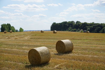 Hay bales on field against sky