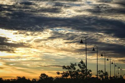 High section of silhouette trees against cloudy sky