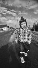 Portrait of cute baby boy walking on road against sky