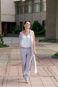 Happy businesswoman smiling while standing in suit on city street.