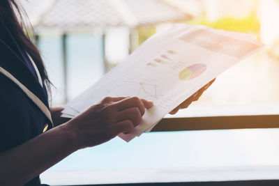 Midsection of woman holding paper
