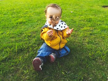 Full length of baby boy holding leaf while sitting on land