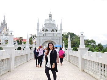 Smiling woman standing on footpath leading towards simala shrine against sky