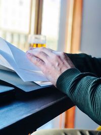Cropped hand of man reading file on table