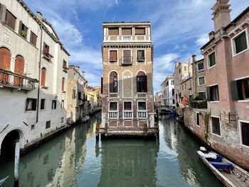 Canal amidst buildings in city against sky