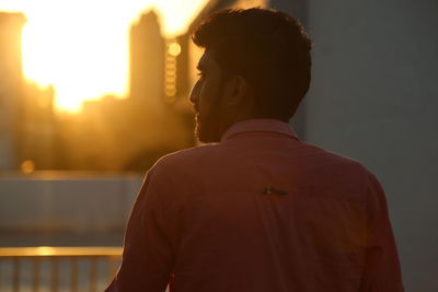 Rear view of man standing against sky during sunset