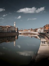 Arch bridge over river against buildings in city