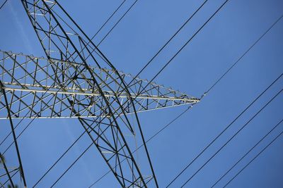 Low angle view of electricity pylon against clear blue sky