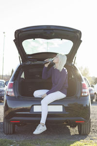 Woman drinking juice from bottle while sitting in car