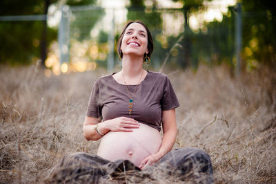 Full length of a smiling young woman sitting on land