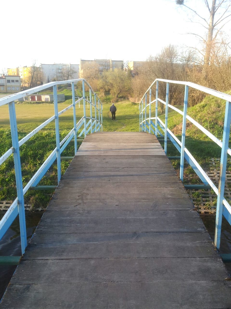 railing, the way forward, footbridge, clear sky, wood - material, boardwalk, bridge - man made structure, built structure, connection, tree, tranquility, wood, nature, water, diminishing perspective, bridge, one person, wooden, day, outdoors