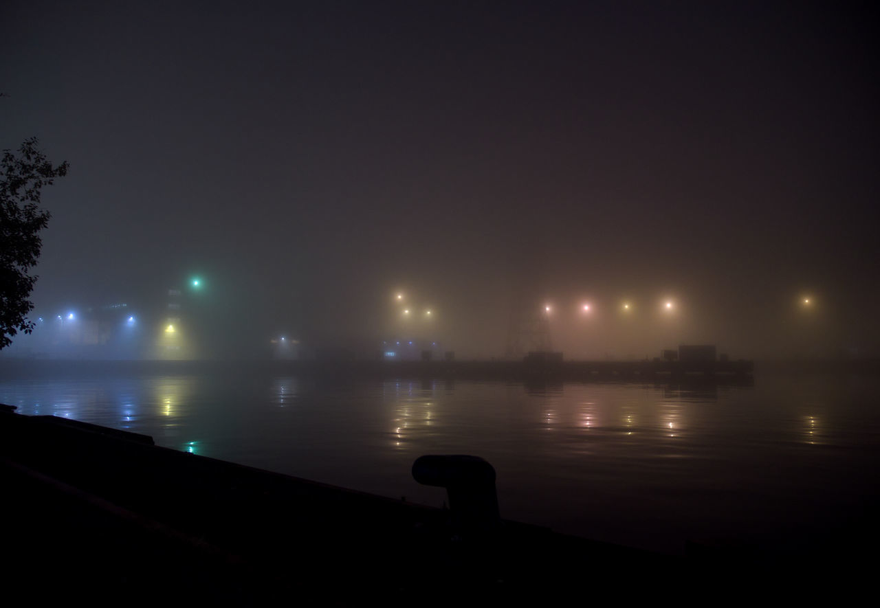 SCENIC VIEW OF ILLUMINATED SEA AGAINST SKY AT NIGHT