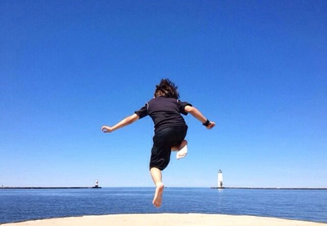 sea, water, full length, clear sky, leisure activity, lifestyles, horizon over water, blue, copy space, beach, enjoyment, vacations, fun, tranquility, tranquil scene, arms outstretched, mid-air, shore