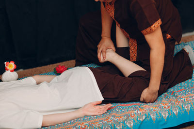 Midsection of couple sitting on bed at home