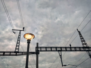 Low angle view of illuminated street light against grey sky