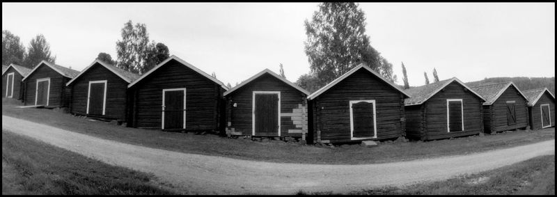 Panoramic shot of cottage by building against sky