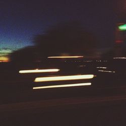 Light trails on road against sky at night