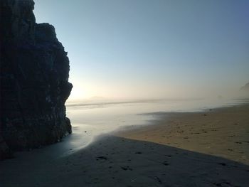 Scenic view of beach against clear sky at sunset