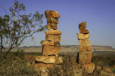 Stack of rocks on field against sky