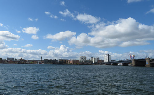 Sea by buildings against sky in city