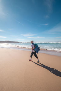 Rear view of woman walking at beach against sky