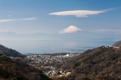 Aerial view of city by sea against sky