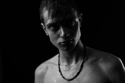 Close-up portrait of young man against black background