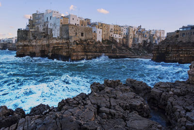 Scenic view of sea by buildings against sky