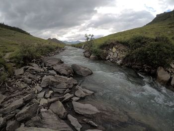 Stream flowing through rocks against sky