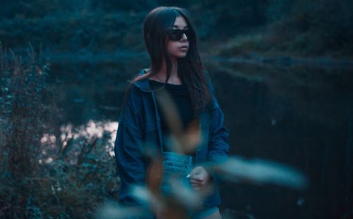 Woman wearing sunglasses while standing at lakeshore