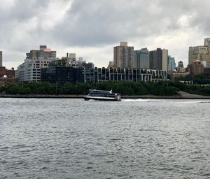 Boats in sea by buildings against sky in city