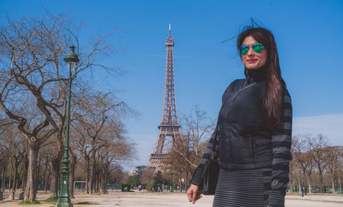 Portrait of smiling young woman standing against eiffel tower