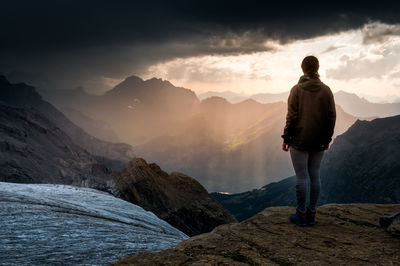 Rear view of man standing on mountain against sky