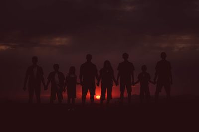 Silhouette people standing on land against sky during sunset