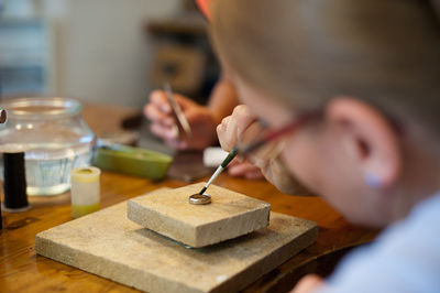 People making wedding ring on table in workshop