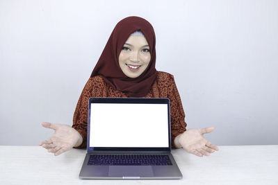 Portrait of smiling young woman using laptop on table