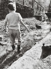 Rear view of boy standing in water