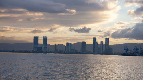 Scenic view of sea by buildings against sky during sunset