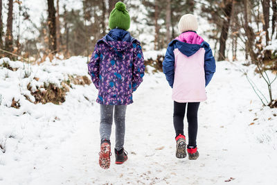 Rear view of women walking on snow covered land