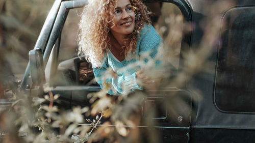 Portrait of smiling young woman standing by railing