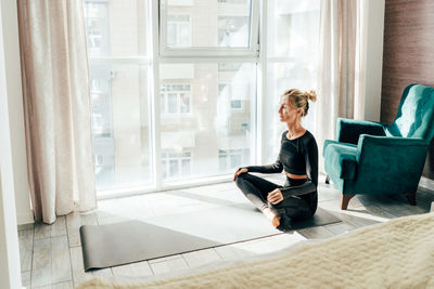 Woman sitting in lotus position on floor at home