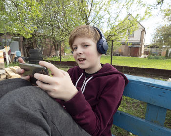 Portrait of boy holding mobile phone while sitting outdoors