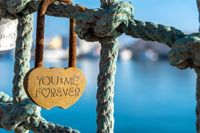 Close-up of a heart-shaped rust padlock with the inscription you and me forever