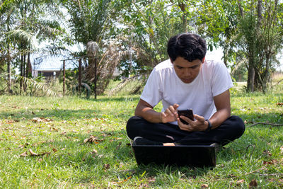 Young man using mobile phone in grass